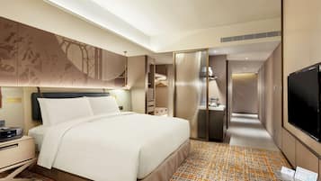 A hotel room with a large bed, bedside table, TV, and a bathroom with a shower and toilet.