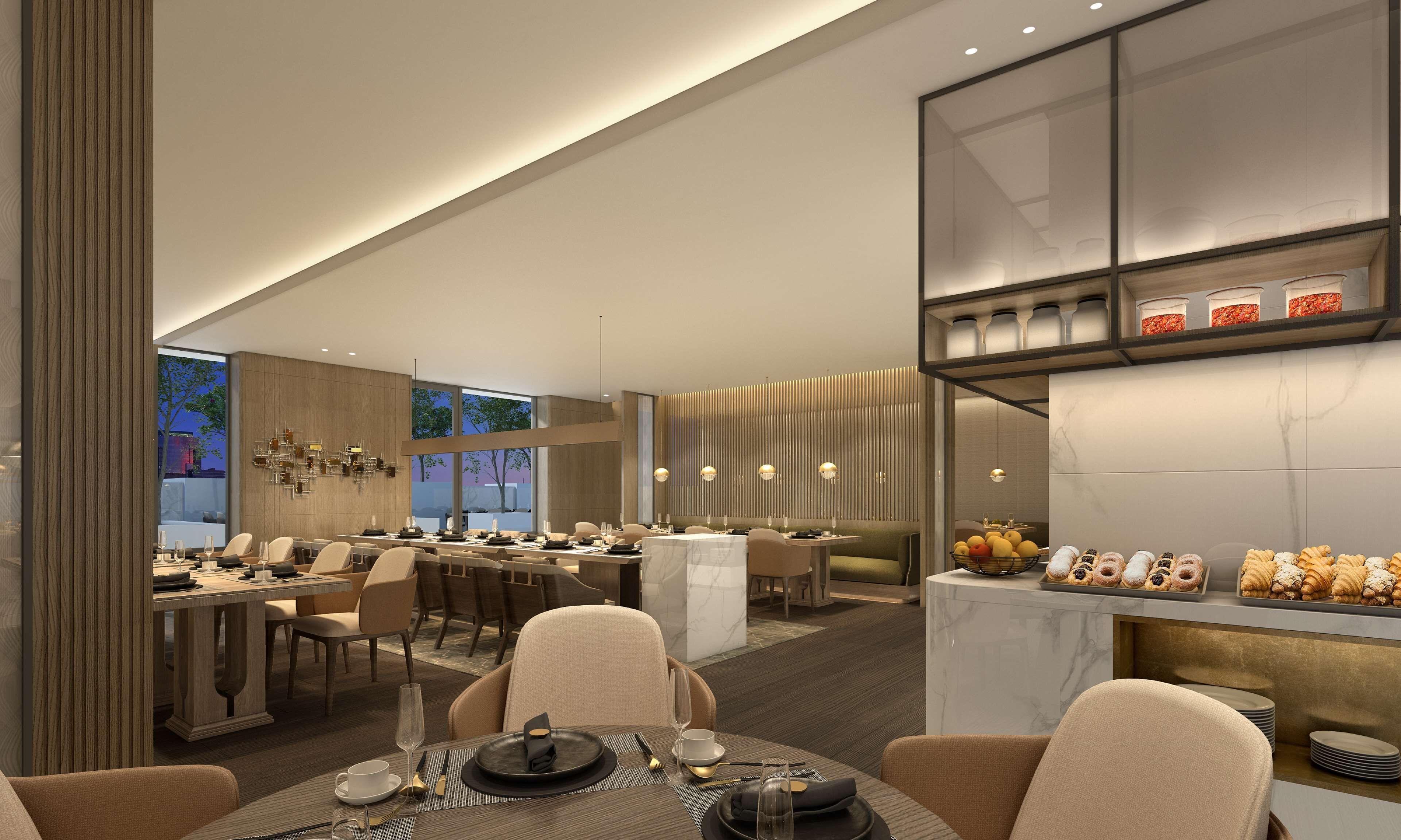 A modern dining area with multiple tables, a central bar, and a dessert display.