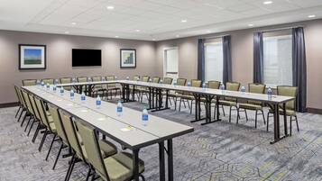 A conference room with a long table, chairs, water bottles, and a carpeted floor.