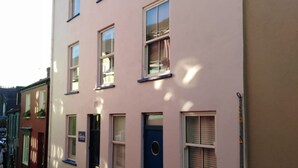 Un immeuble à plusieurs étages, doté d’une façade rose, de nombreuses fenêtres et d’une porte bleue.