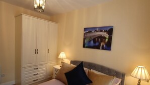 Une chambre à coucher comprenant un lit, deux lampes de chevet, une table de chevet, une armoire et un tableau accroché au mur.