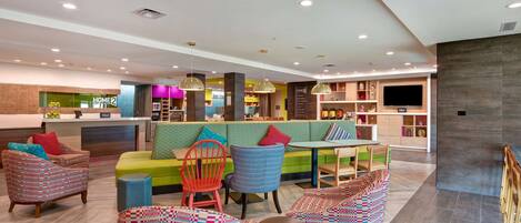 A modern interior with a reception area, seating arrangements, and a television screen.