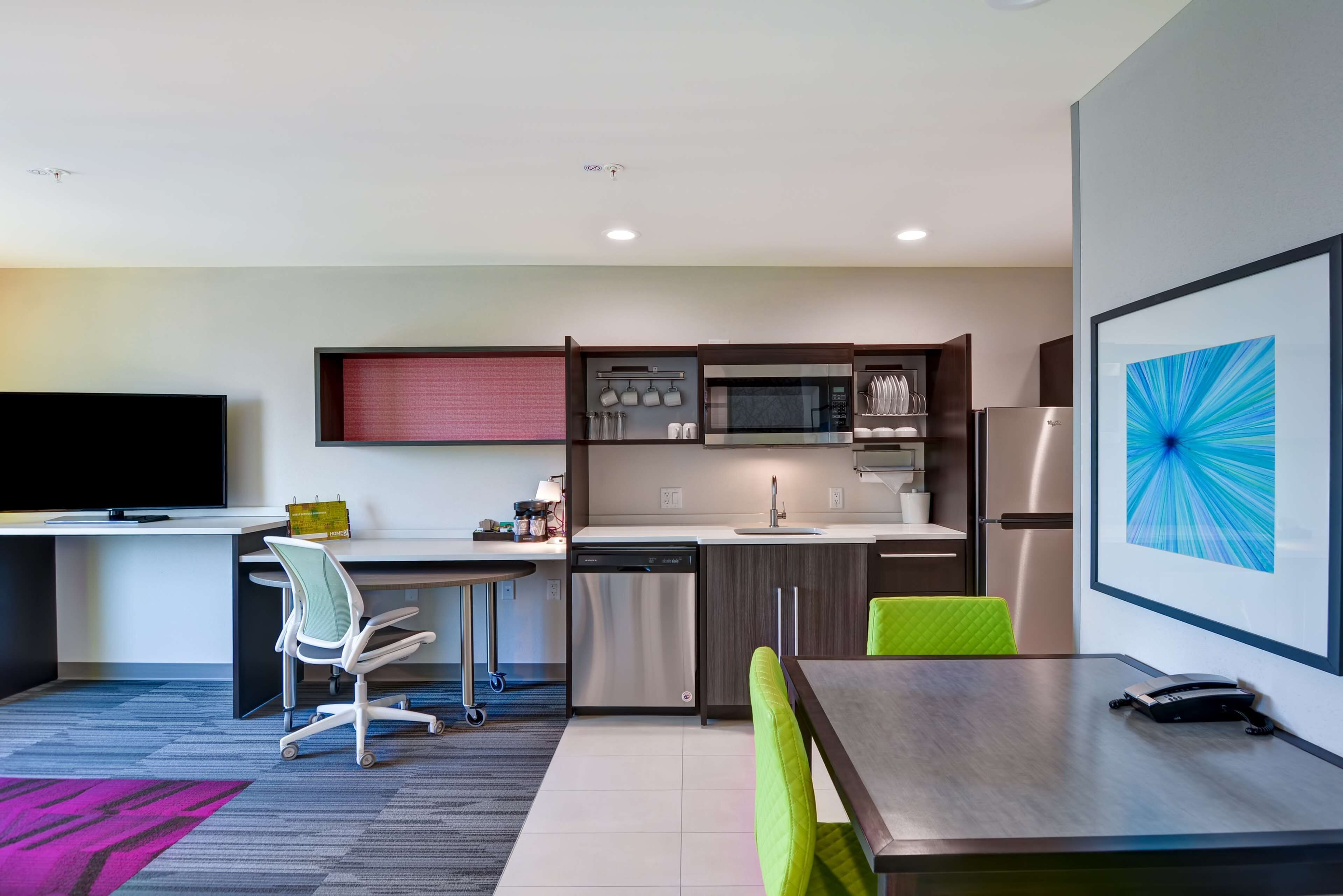 A modern kitchen with a microwave, sink, and dishwasher. There is a dining area with a table and chairs.