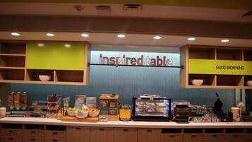 A breakfast buffet area with a sign reading "Inspired Table" and a "Good Morning" sign.