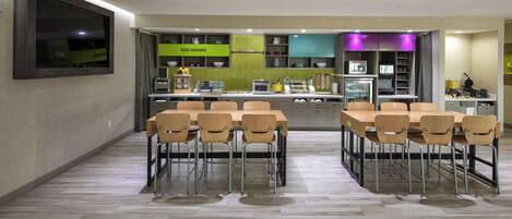 A modern kitchen with a breakfast bar, wooden chairs, and built-in appliances.