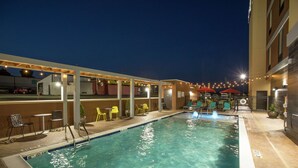Una piscina amb una font d'aigua, envoltada de mobiliari exterior i llums penjants.