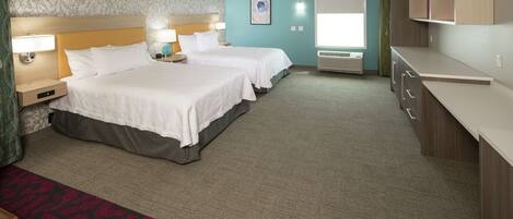 A hotel room with two beds, a desk, a wardrobe, and a window with curtains.