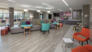 Rebedor modern d'un hotel amb un sofà, cadires, una taula petita i una recepció.