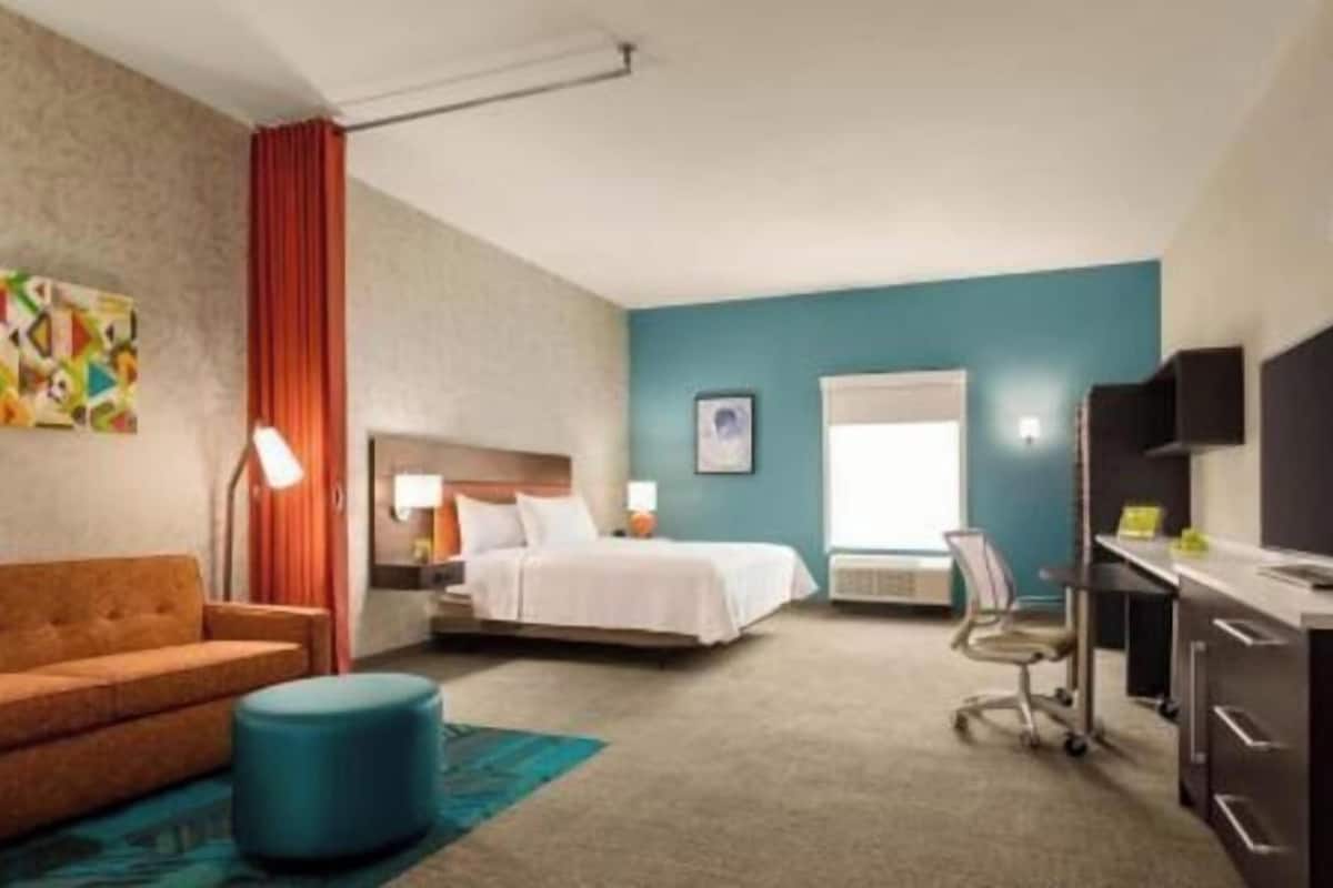 A hotel room with a bed, a desk, a television, and a sofa.