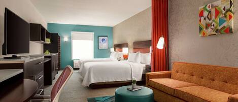 A hotel room with a bed, a desk, a chair, a sofa, and a television.