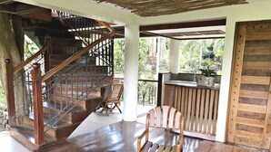 Un escalier en bois menant à un balcon d’où l’on peut admirer la verdure.