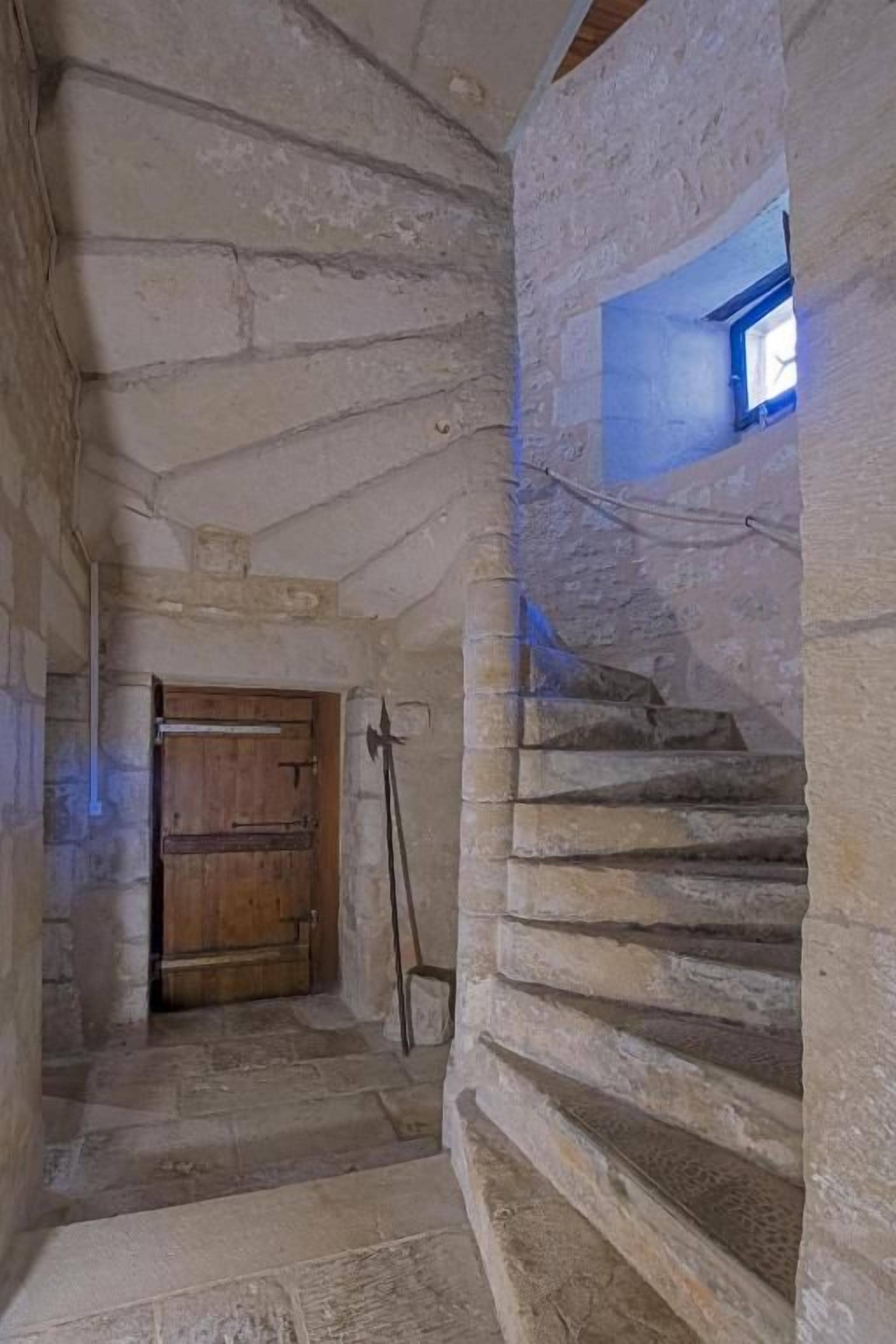 A stone staircase with a wooden door at the top and a small window at the bottom.