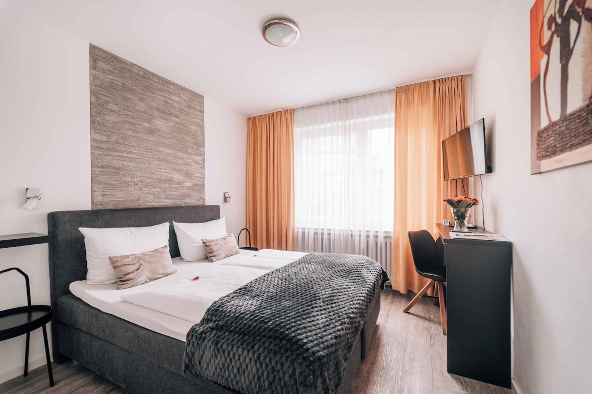 Una moderna camera d'albergo con un letto grande, una scrivania, una sedia e un televisore appeso al muro.