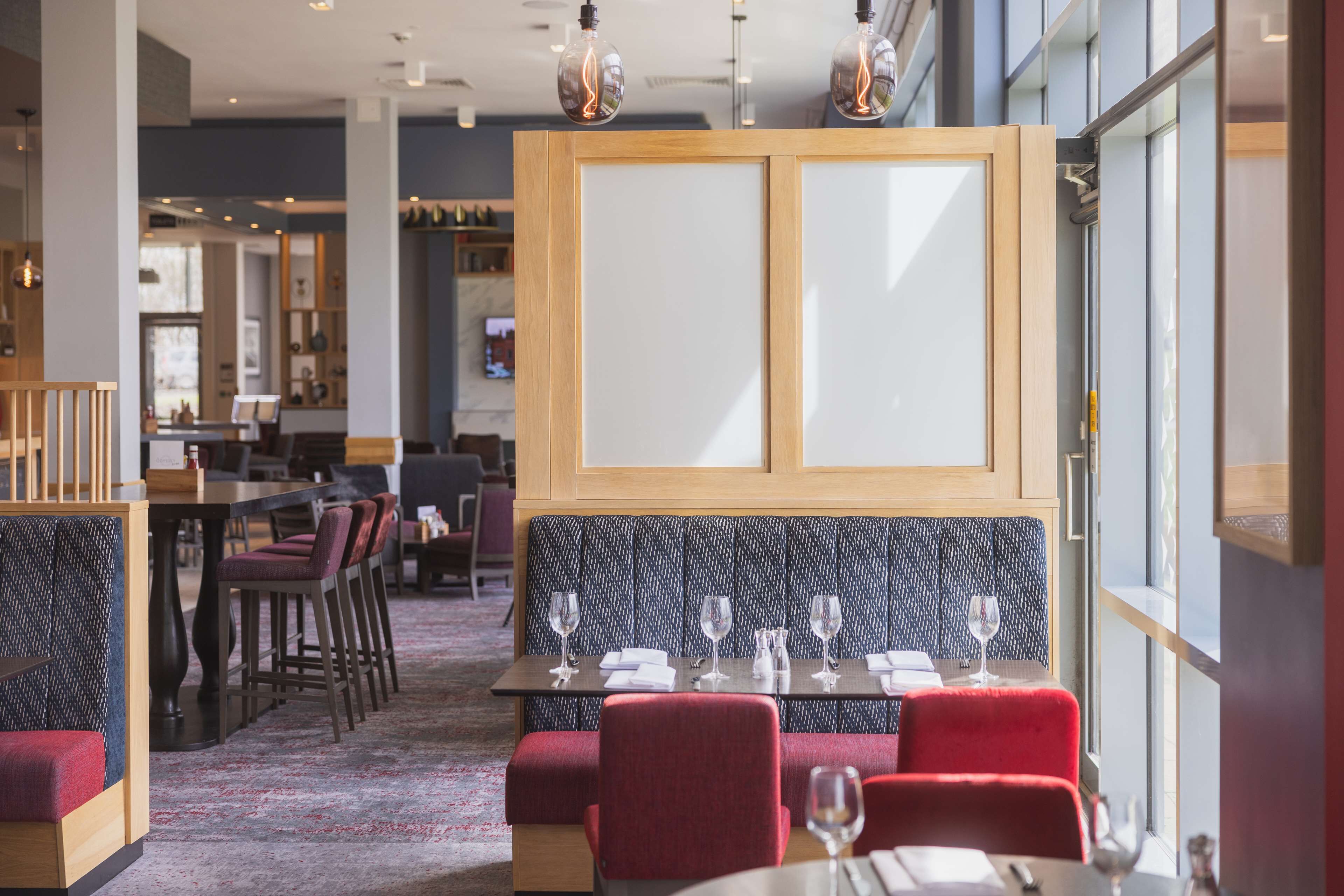 Un restaurant avec des banquettes, des tables hautes et un coin bar.