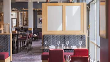Un restaurant avec des banquettes, des tables hautes et un coin bar.