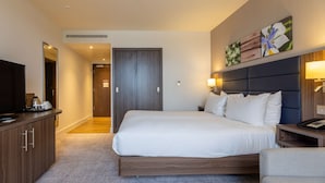 Une chambre d’hôtel avec un grand lit, une télévision, un bureau et une armoire.