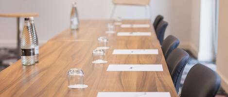 Una sala de conferencias con una larga mesa de madera, varias sillas y una botella de agua.