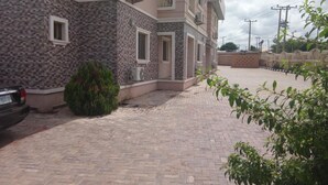 A multi-story building with a tiled facade, a paved driveway, and a parked car. - Viclin Diamond Hotels (Abuja)