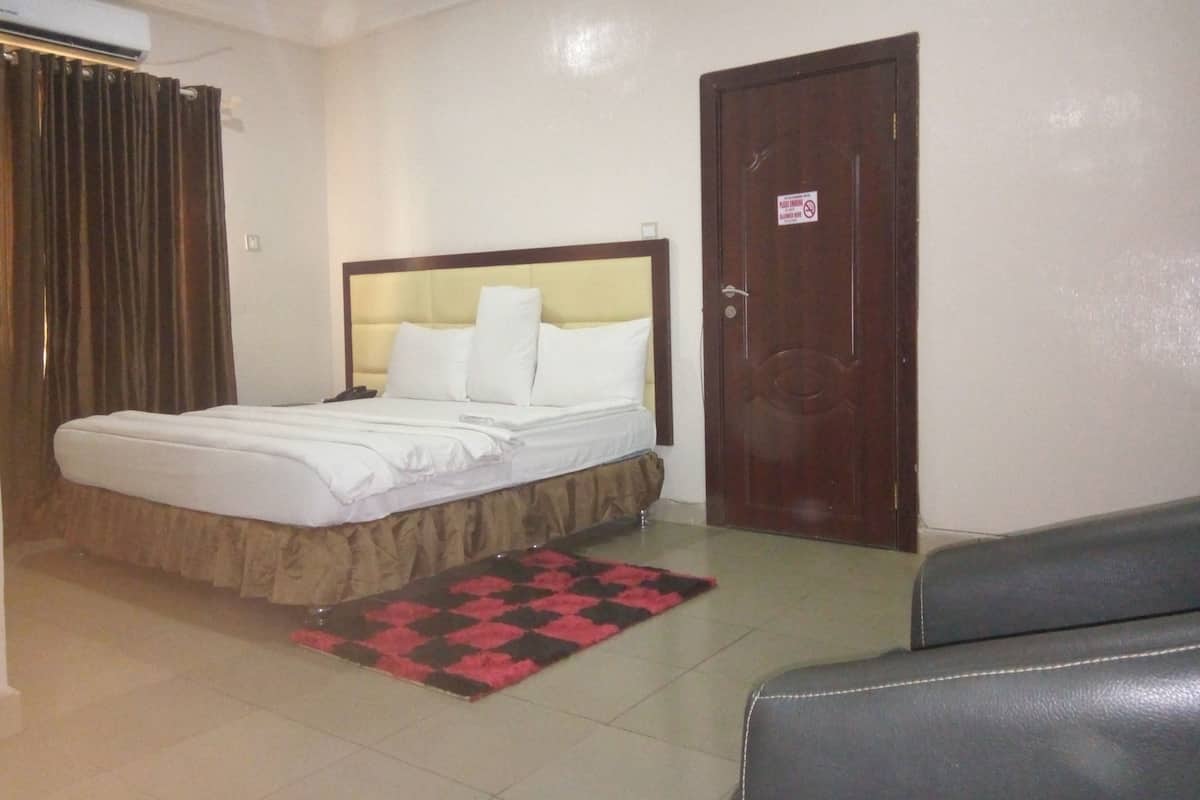 A hotel room with a bed, a wooden door, and a small seating area.