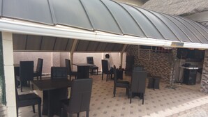 An outdoor patio area with tables and chairs under a curved roof, a brick wall, and a sign indicating a VIP lounge. - Viclin Diamond Hotels (Abuja)