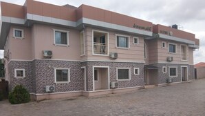 A multi-story building with a flat roof, air conditioning units, and a paved entrance area. - Viclin Diamond Hotels (Abuja)