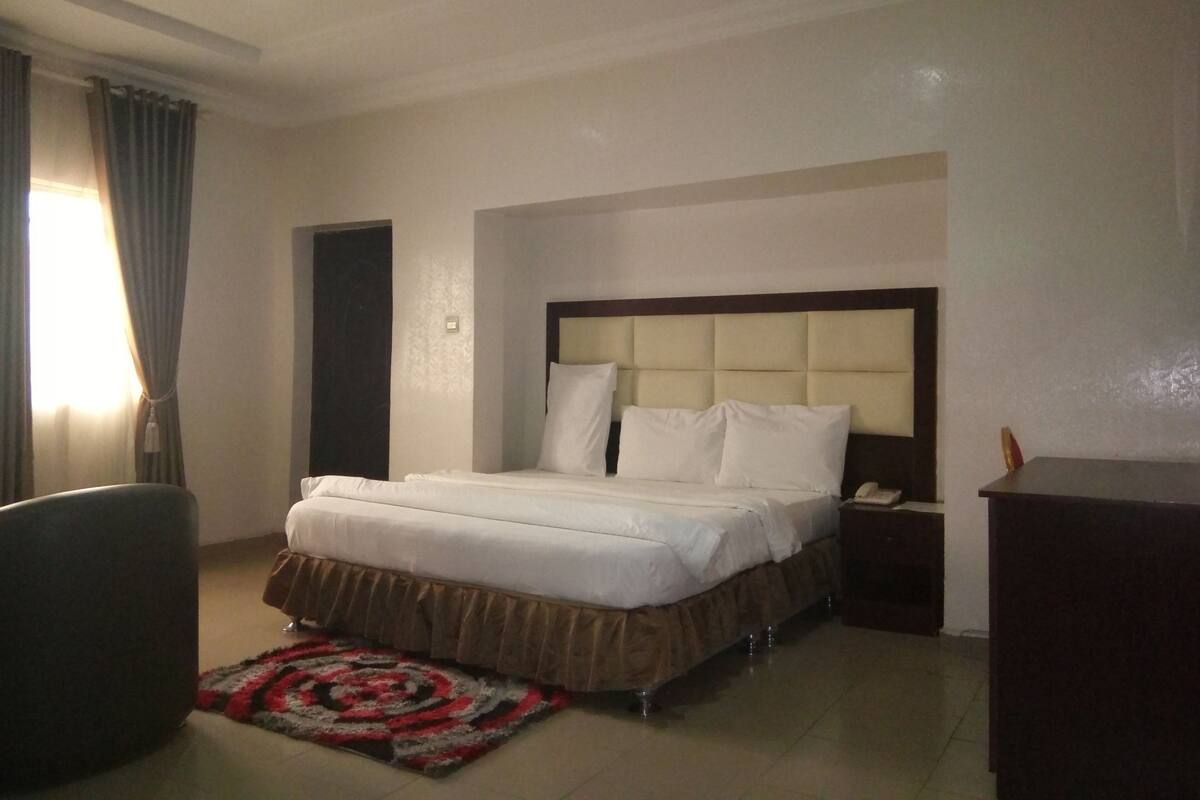 A hotel room with a bed, bedside table, and a desk.