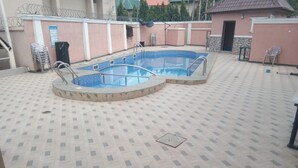 A swimming pool with two separate sections, surrounded by a tiled deck. - Viclin Diamond Hotels (Abuja)