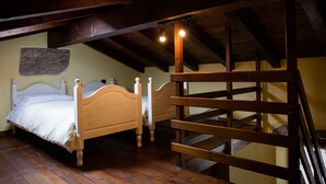 Un dormitorio con dos camas de madera, una pared de piedra y una escalera de madera.