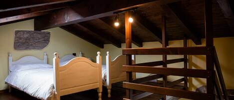 Un dormitorio con dos camas de madera, una pared de piedra y una escalera de madera.