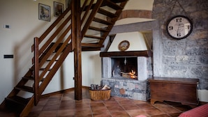 Una escalera de madera que conduce a una chimenea de piedra con un reloj en la pared.