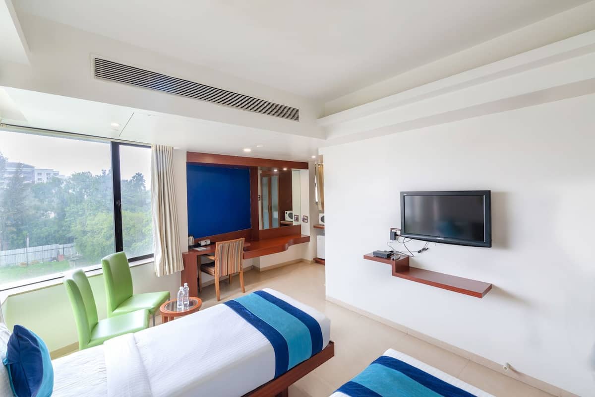 A hotel room with a bed, a TV, a desk, and a chair.