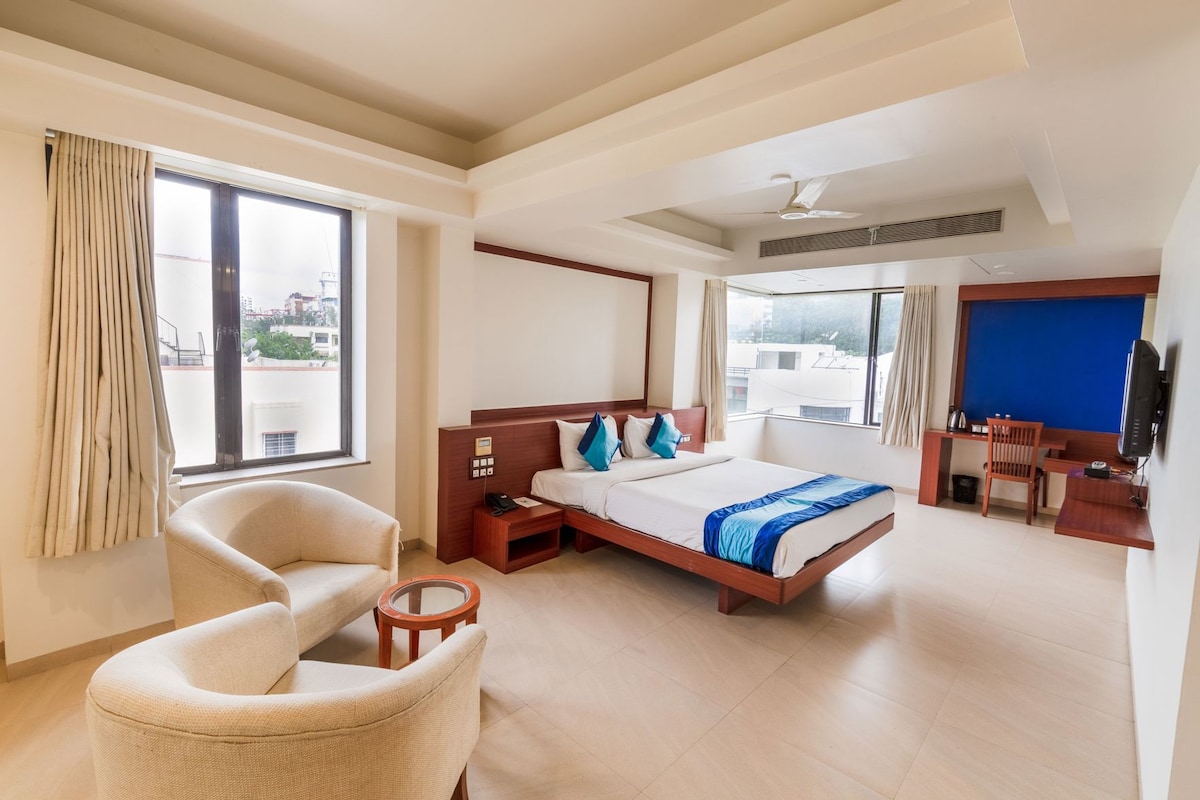 A hotel room with a bed, a desk, a chair, and a television.