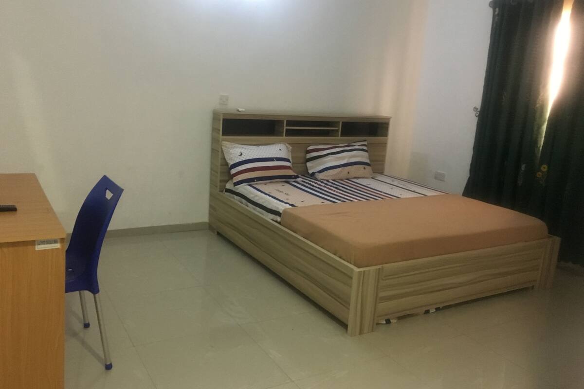 A bedroom with a bed, a desk, and a chair.