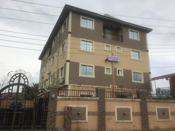 A multi-story hotel with a stone facade, multiple balconies, and a gated entrance.