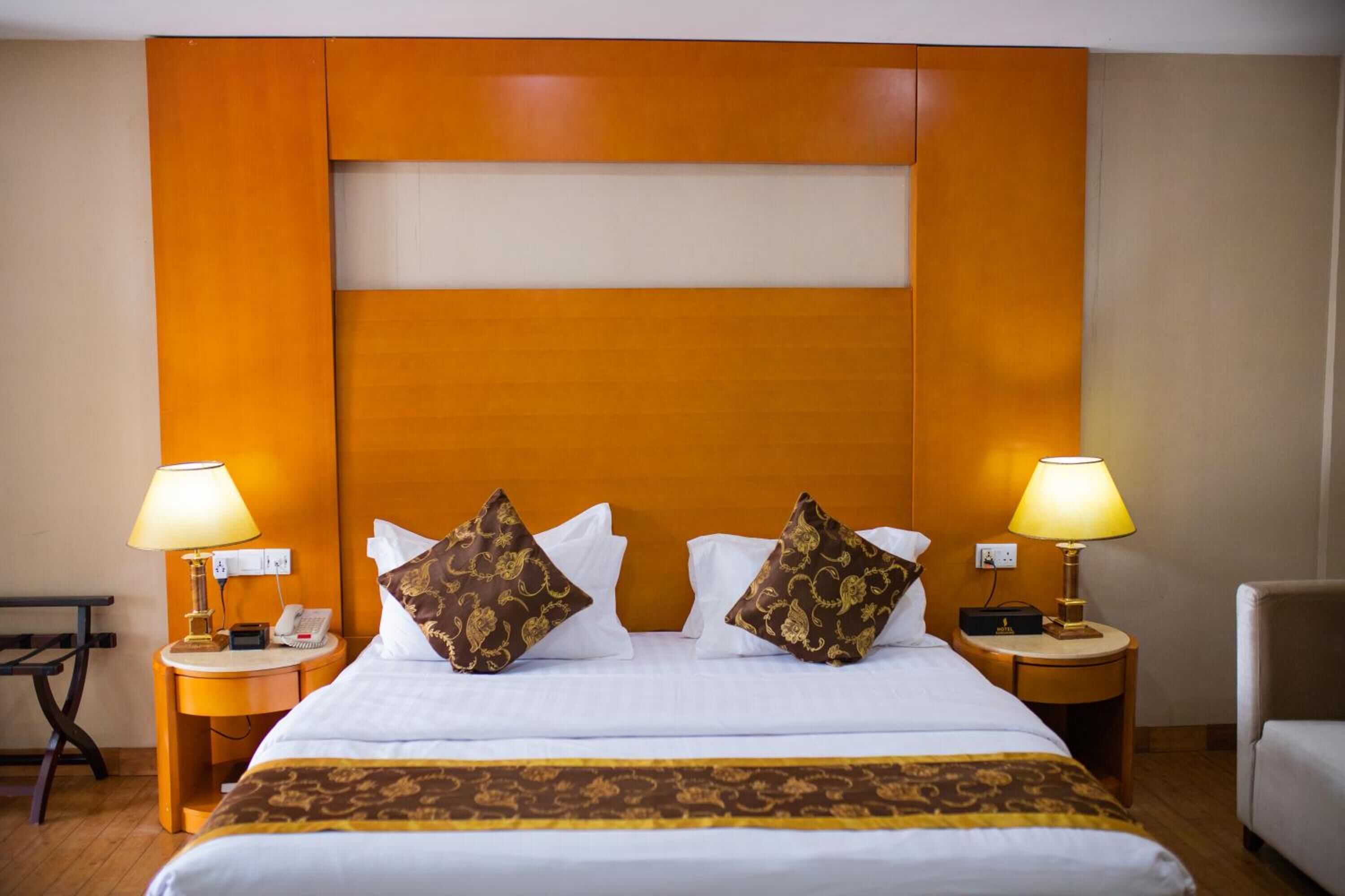 Una camera d'albergo con un letto grande, due comodini con lampade, un telefono e una sedia.