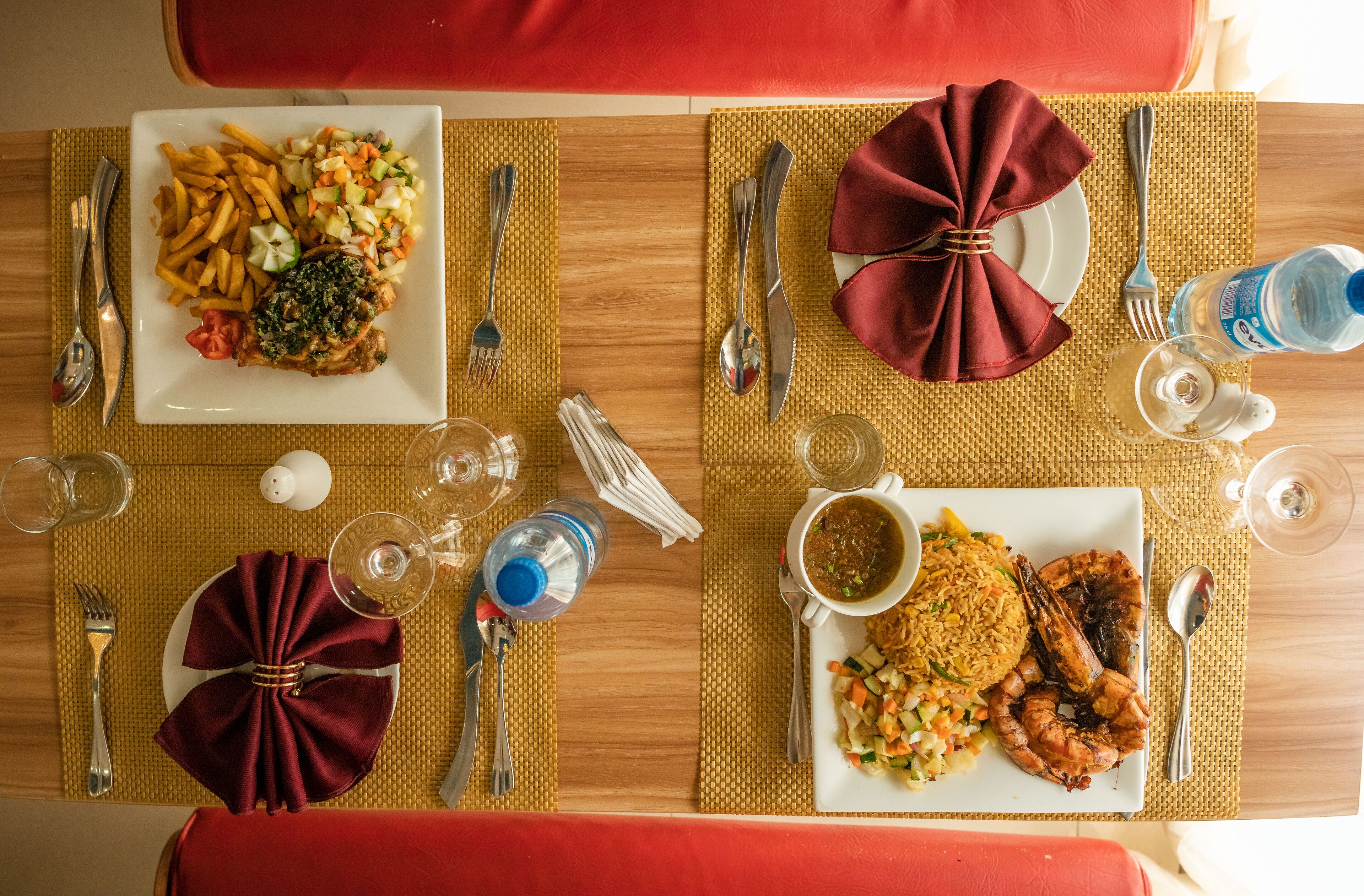 A dining table set with plates of food, cutlery, and glasses.