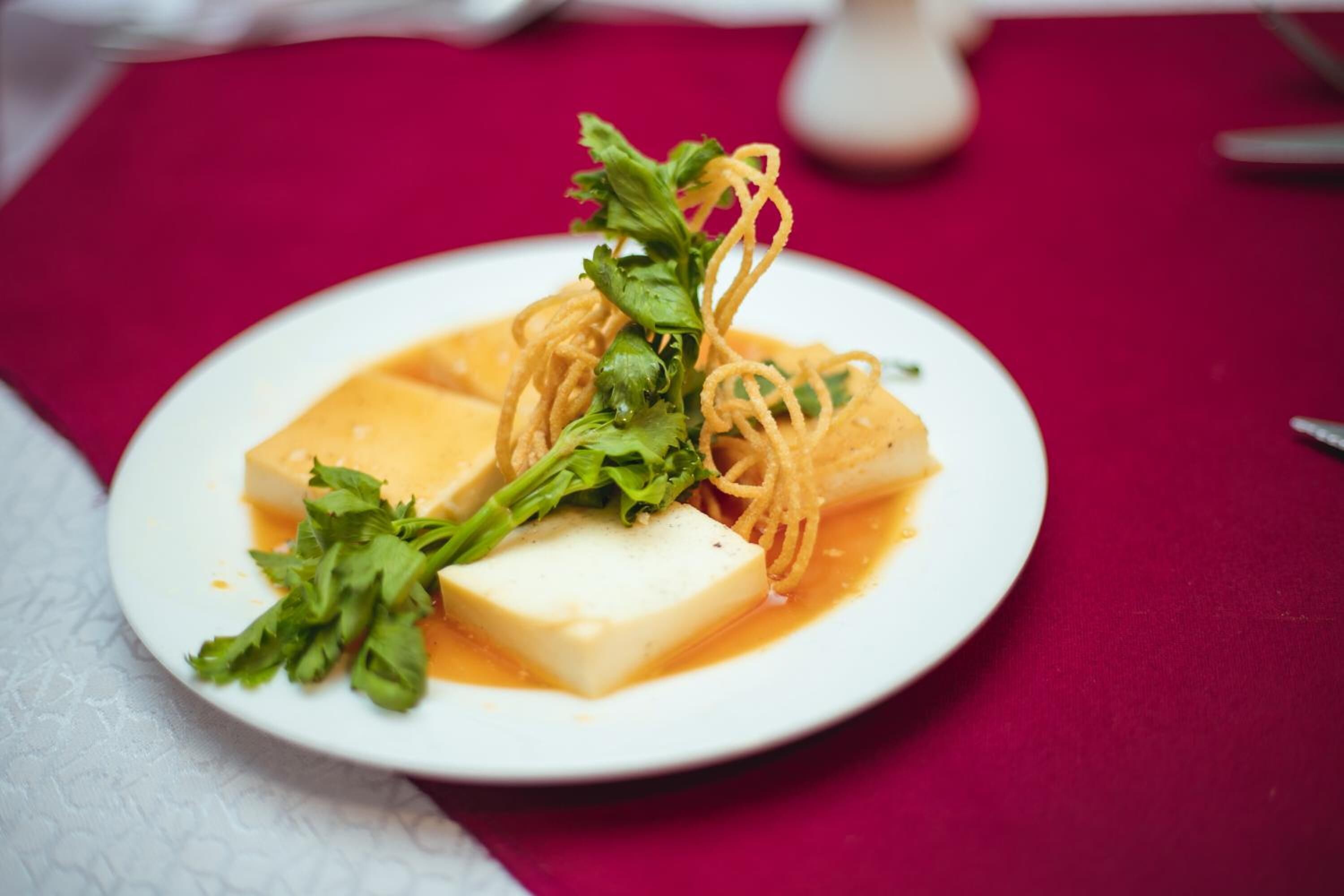 Egy fehér tányéron tálalt étel, melyet tofu és tészta tesz ki.