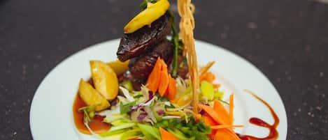 A plate of food with various vegetables and a piece of meat, possibly steak, on a white plate.