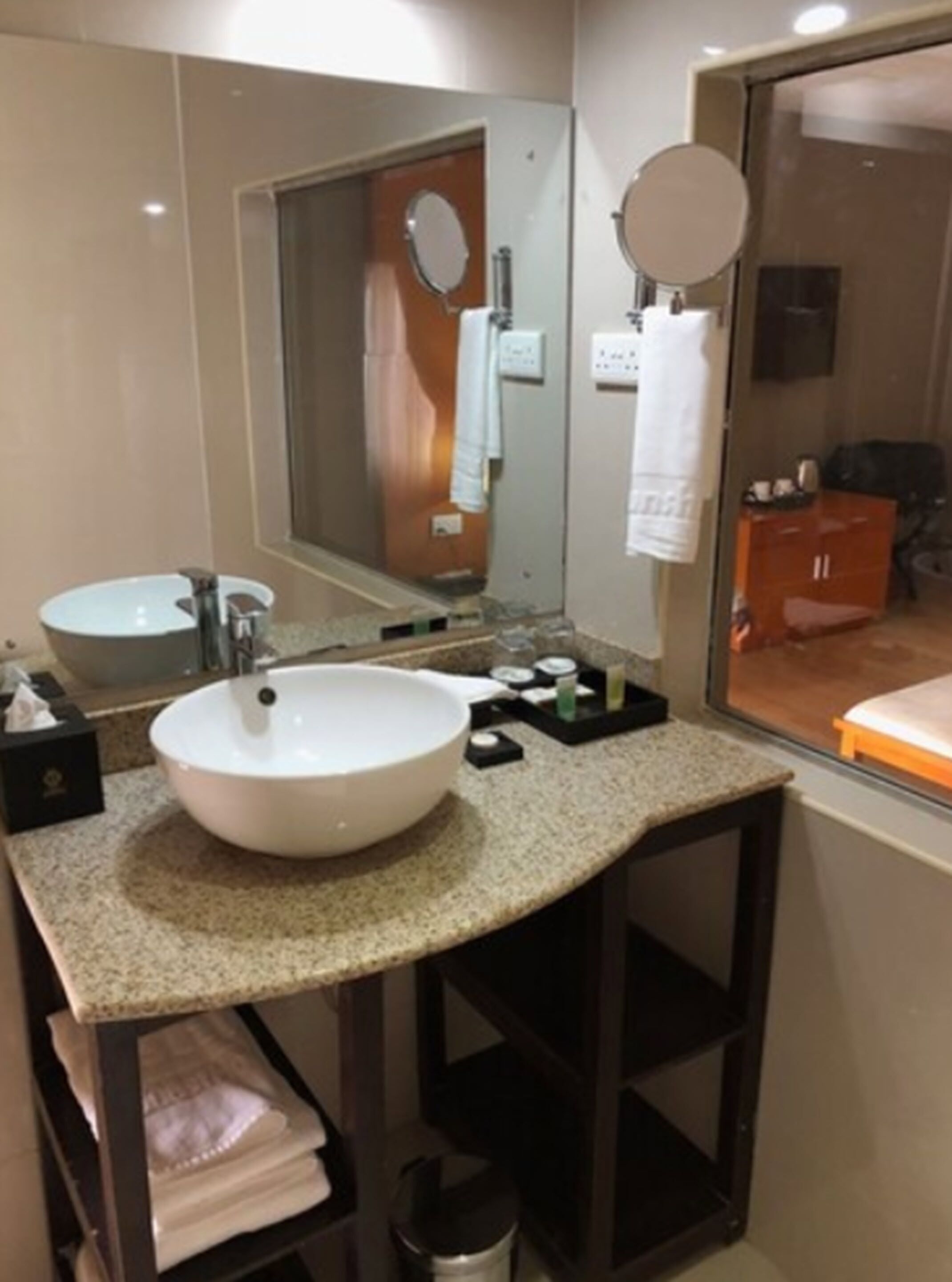 Un baño moderno con un lavamanos blanco grande, un espejo y un mueble de tocador con un perchero para toallas.