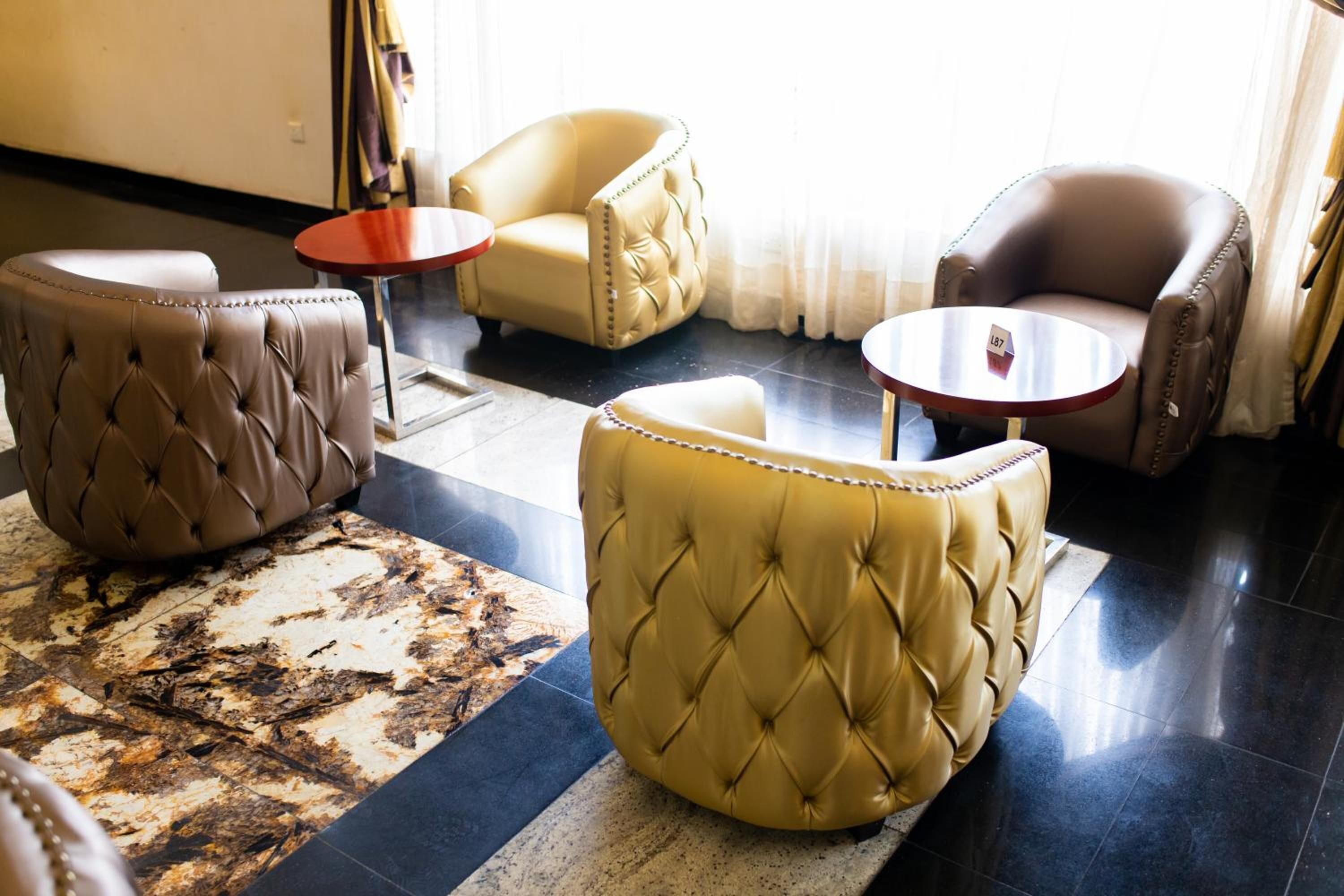 A modern hotel lobby with leather armchairs, a patterned rug, and a small table.