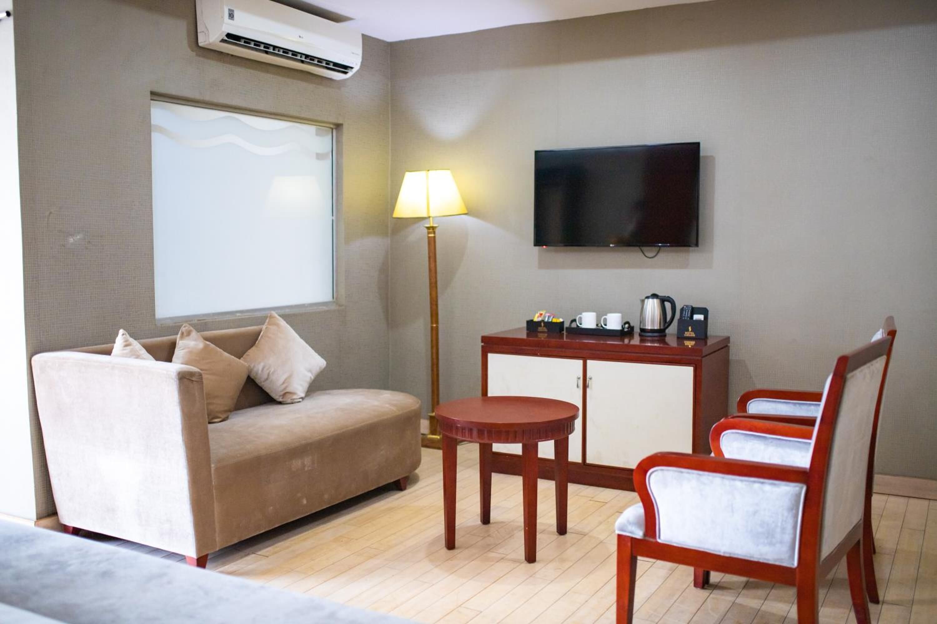 A hotel room with a sofa, a small table, a TV, and a cabinet.