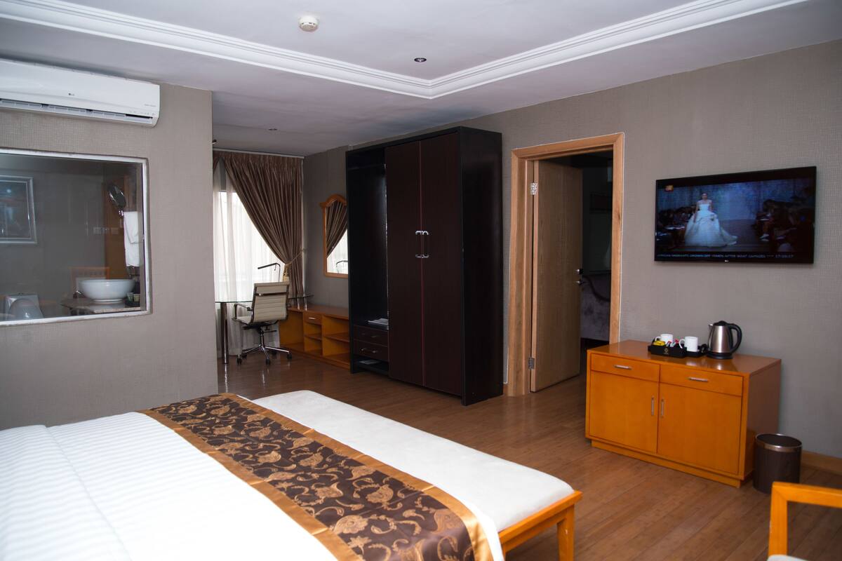 A hotel room with a bed, a wardrobe, a television, and a desk.