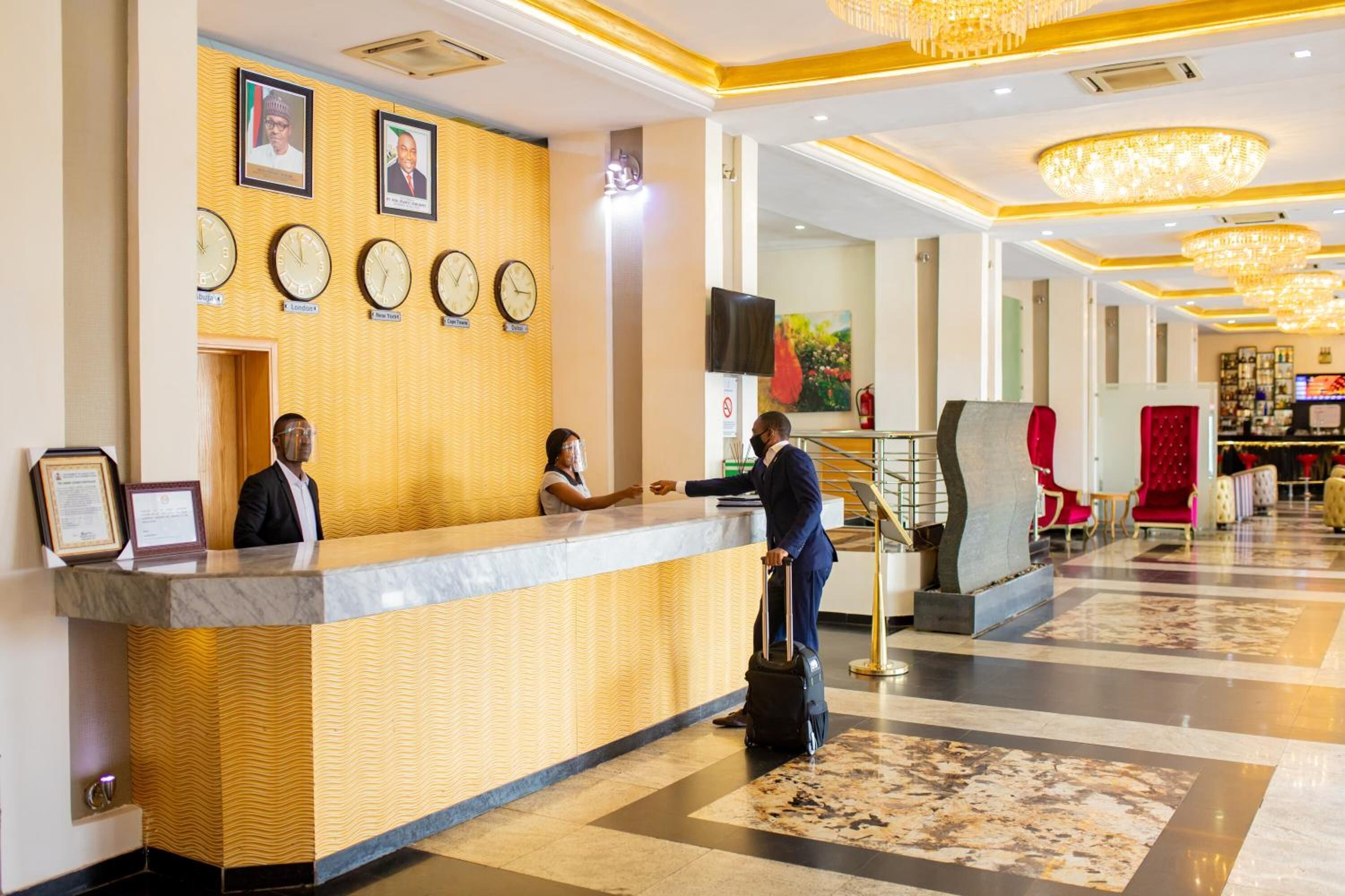 Un hall d’hôtel comprenant un comptoir d’accueil, des horloges et un grand lustre.