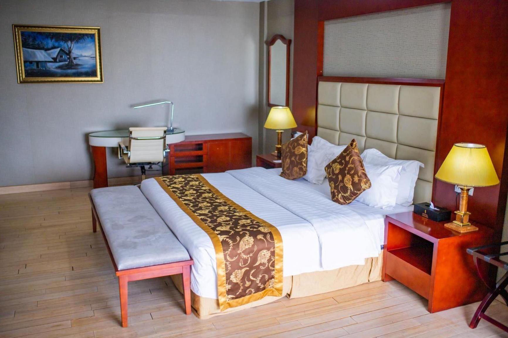 A hotel room with a large bed, bedside tables, a desk, and a chair.