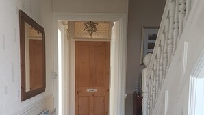 Un couloir doté d’un revêtement de sol à motifs, une porte en bois portant l’inscription « Privé », et une rambarde blanche sur le côté droit.