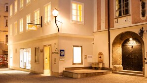 A multi-story hotel with a ground-floor entrance, a visible reception area, and a well-lit facade. - Hapimag Resort Salzburg (Salzburg)