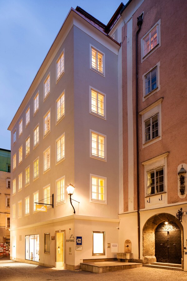 Un hotel de varios pisos con entrada a nivel de calle, recepción visible y fachada bien iluminada.