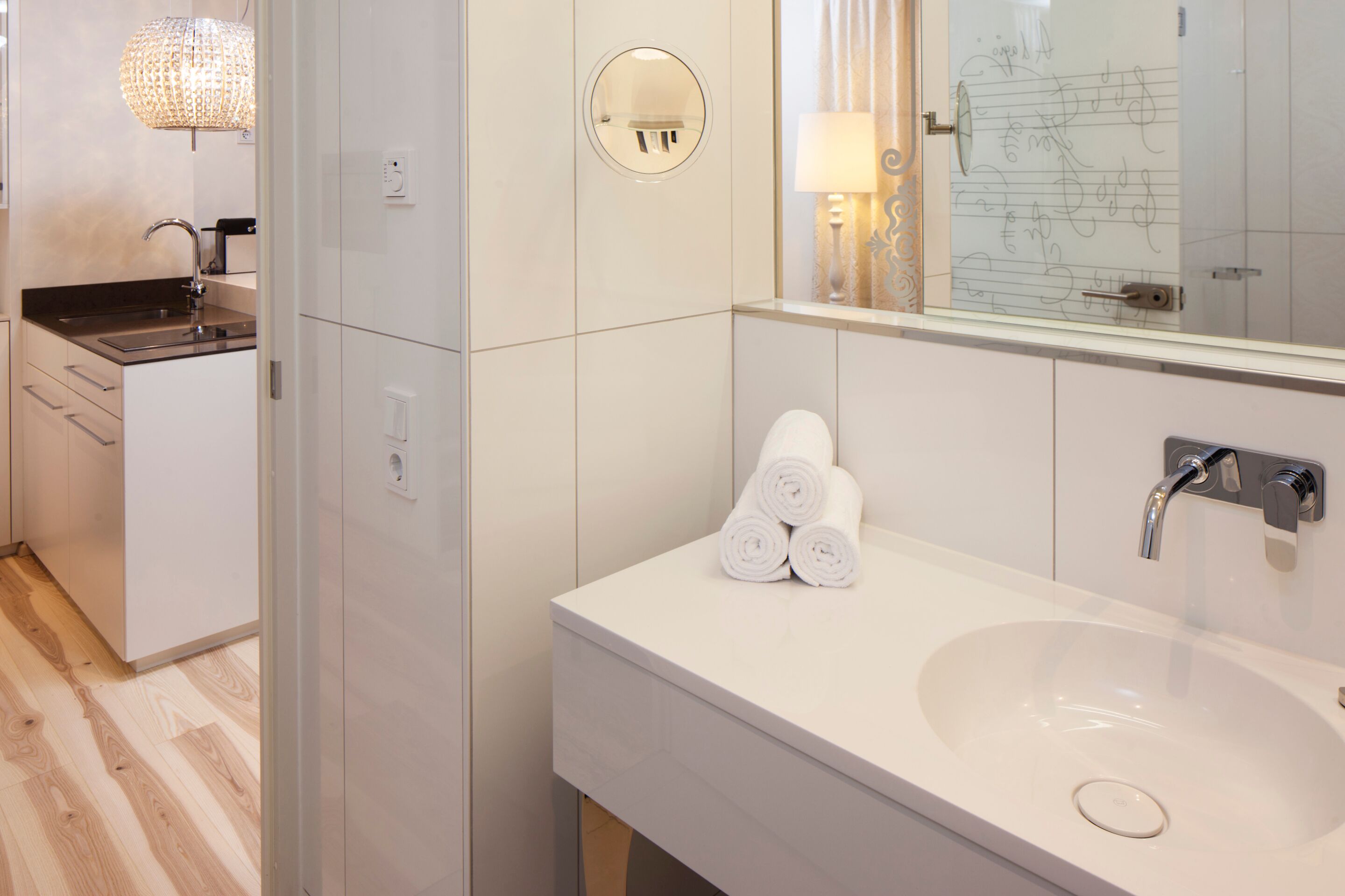 Un baño moderno con un lavabo blanco, un espejo y un perchero para toallas.