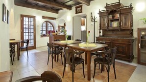 A dining area with a wooden table and chairs, a wooden cabinet with books, and a chandelier. - Staroměstský penzion (Tabor)