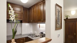 A kitchen with wooden cabinets, a granite countertop, a sink, and a vase with flowers. - Staroměstský penzion (Tabor)